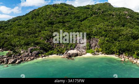 Une scène de plage magnifique avec des eaux turquoises claires, de grands rochers et une végétation dense le long du littoral. Praslin, Seychelles. Banque D'Images