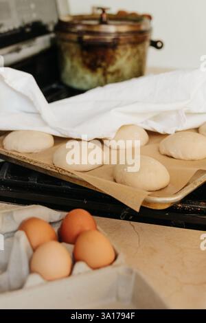 Les petits pains au levain se lèvent sur le poêle recouvert d'un torchon Banque D'Images