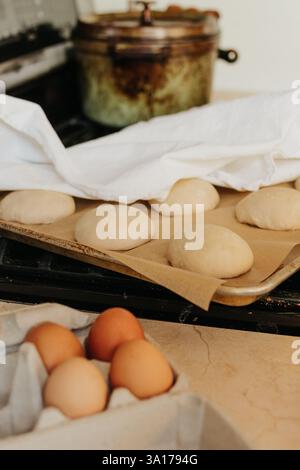 Les petits pains au levain se lèvent sur le poêle recouvert d'un torchon Banque D'Images