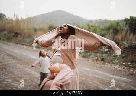 Enfants noirs dansant dans la langue de la pluie se sentant joie maman enceinte Banque D'Images