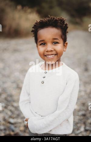 Portrait beau garçon noir de 5 ans souriant à l'extérieur en résumé Banque D'Images