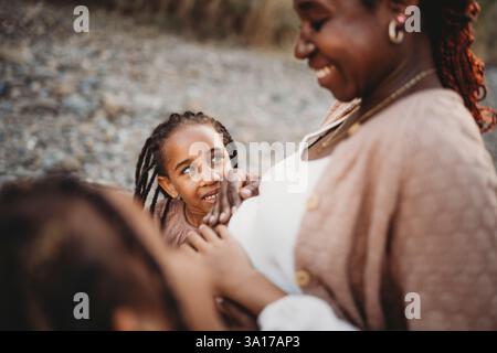 Heureux mélange souriant course enfants mains sur le ventre de maman enceinte noir Banque D'Images