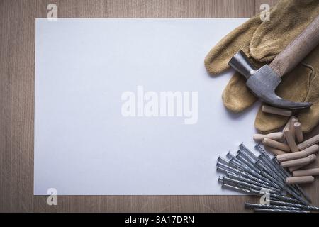 Feuille propre de clous en acier de papier griffe marteau goupilles en bois et gants de sécurité en cuir sur le concept de construction copyspace de panneau de bois Banque D'Images
