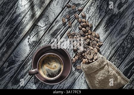 Café fraîchement infusé dans une tasse brune et haricots rôtis versés à partir de Sack Banque D'Images