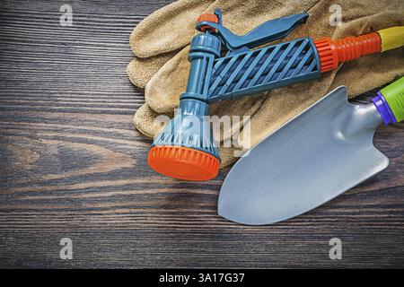 Gants de sécurité de buse de pulvérisation de jardin pelle à main sur le concept d'agriculture de planche en bois Banque D'Images