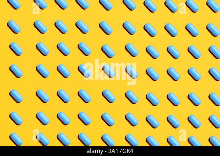 Pilules bleues en rangées sur fond jaune, mise en page créative. Médecine, concept de santé Banque D'Images