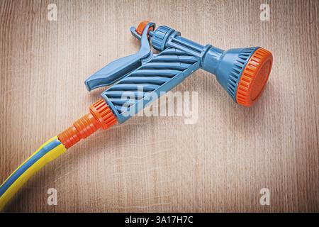 Pistolet de pulvérisation à main de tuyau d'arrosage sur le concept de jardinage de planche en bois Banque D'Images