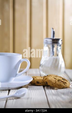 Tasse avec biscuits et distributeur de sucre sur la table Banque D'Images