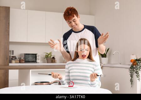 Jeune homme proposant à sa copine mécontentait dans la cuisine Banque D'Images