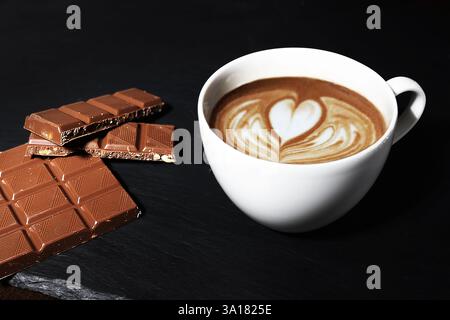 une tasse de cappuccino avec une barre de chocolat au lait. coeur sur mousse de cappuccino. barista Banque D'Images