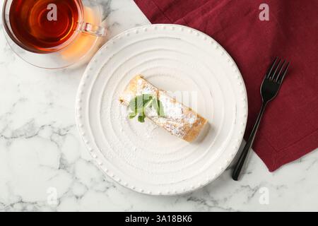 Morceau de strudel de pomme savoureux servi avec du thé sur une table en marbre blanc, plat Banque D'Images