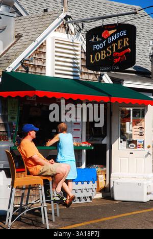 Un homme adulte attend sa femme devant une cabane à homard sur la côte du Maine Banque D'Images