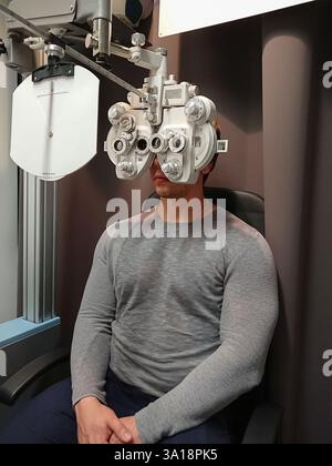 Homme dans une clinique professionnelle portant un phoroptre pour l'évaluation de l'oeil, le test de vision et les mesures précises de lentille. Concept d'amélioration de la vision Banque D'Images