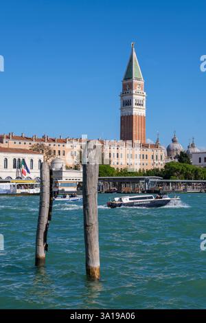 Venise, Italie - 12 octobre 2024 : le Campanile Saint-Marc et les dômes de la Basilique di San Marco s'élèvent au-dessus du front de mer vénitien sous un ciel bleu clair. Banque D'Images