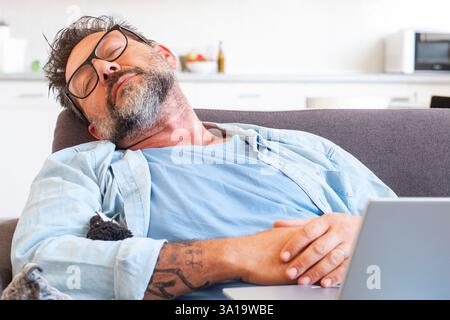 Notion de nécessité de se reposer au travail. Fatigué gestionnaire épuisé vêtu de vêtements formels dort sur un canapé dans son bureau moderne Banque D'Images