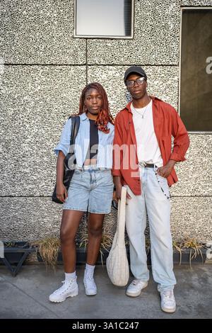 Couple afro-américain sérieux confiant dans des vêtements tendance chic. Mur de la toile de fond du bâtiment de la ville Banque D'Images