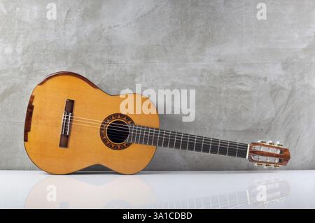 Instrument de musique - guitare classique sur un fond de table blanc d'un mur de béton Banque D'Images