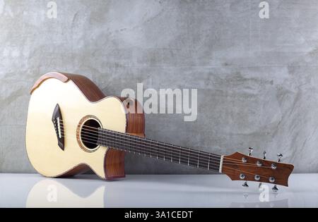 Instrument de musique - guitare acoustique top épicéa solide sur fond de mur en béton. Banque D'Images