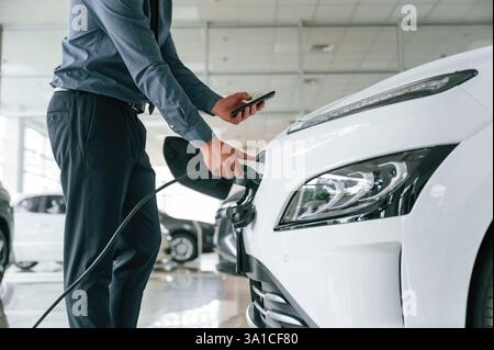 Vue rapprochée de l'homme qui est avec la voiture électrique. Banque D'Images