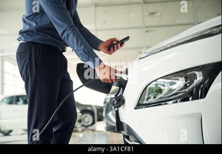 Vue rapprochée de l'homme qui est avec la voiture électrique. Banque D'Images