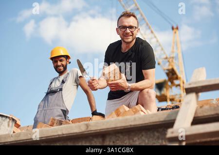 L'homme en lunettes est debout avec un indien sur le chantier de construction. Banque D'Images