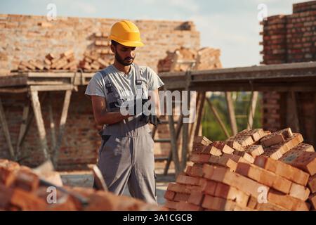 Porter les gants. Bel homme indien est sur le chantier de construction. Banque D'Images