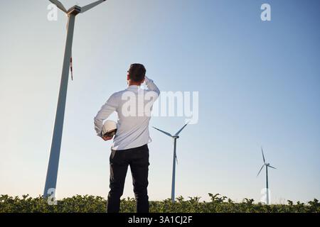 En regardant vers l'avenir. Le technicien de maintenance est sur le terrain avec des moulins à vent. Banque D'Images