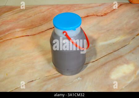 Un récipient en plastique avec un couvercle bleu repose sur un comptoir en marbre. Le couvercle est fixé au récipient avec une poignée rouge Banque D'Images