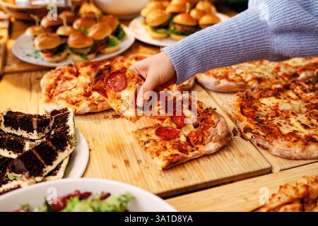 Pizza Slice à la main avec collations assorties sur la table à manger en bois Banque D'Images