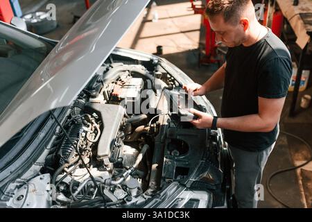 Sous le capot. L'homme travaille dans le salon de réparation automobile. Banque D'Images