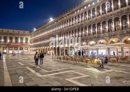 Piazza San Marco la nuit dans la ville de Venise, Italie. Place Saint-Marc avec tables de restaurant en plein air. Banque D'Images
