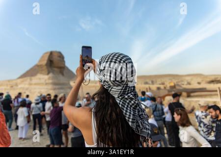 Gizeh, Egypte ; 20 janvier 2024 : témoin d'une femme touristique capturant le Sphinx et les célèbres pyramides de Gizeh, Egypte, dans le désert. Vivez l'intemporel Banque D'Images