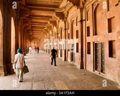 Les gens marchent à travers un couloir de grès rouge à colonnades dans le complexe historique de Fatehpur Sikri, Uttar Pradesh, Inde. Banque D'Images