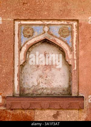 Motif floral délavé et arc sur un mur altéré dans le complexe Fatehpur Sikri, Uttar Pradesh, Inde. Banque D'Images