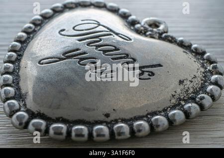 Article en forme de coeur en argent antique avec inscription de remerciement sur fond en bois. Banque D'Images