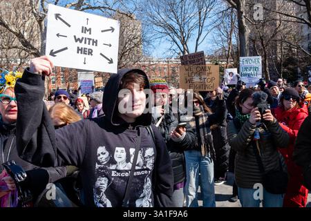 New York, NY, États-Unis. 8 mars 2025. Des milliers de femmes et de sympathisants se sont rassemblés à Washington Square Park pour un rassemblement et une marche vers Union Square pour soutenir les droits des femmes, des gays, des transgenres et des personnes à l'occasion de la Journée internationale de la femme. Lorelei Crean, lycéenne de 17 ans et militante trans, tient une pancarte qui indique « je suis avec elle », avec des flèches pointant dans toutes les directions. Crédit : Ed Lefkowicz/Alamy Live News Banque D'Images