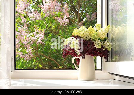 Bouquet avec des fleurs de lilas printanières dans un vase sur une fenêtre ensoleillée, arrangement floral abstrait, nature morte avec des branches d'arbre fleuries, esprit intérieur de la maison Banque D'Images