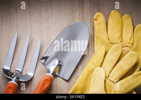 Fourche à truelle en métal à bêche à main et gants de sécurité en cuir sur concept de jardinage en planche de bois Banque D'Images