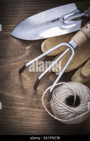 Paire de gants de jardinage en cuir marron à pelle à main en métal et hank de corde sur le concept d'agriculture de planche en bois vintage Banque D'Images