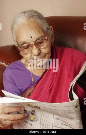 Une femme maharashtrienne de 92 ans lisant le journal, Inde MR#686J. Banque D'Images