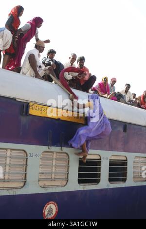 Les gens traînant une vieille femme essayant de grimper sur le toit du train sur la gare, Jodhpur, Rajasthan, Inde, Asie Banque D'Images