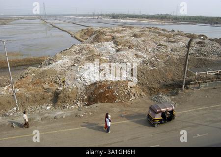 Les camions déversent des débris sur la terre de salin sur l'autoroute Eastern Express à Bombay Now Mumbai, Maharashtra, Inde, Asie Banque D'Images