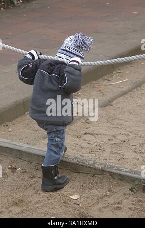 Petit garçon de deux ans et demi debout, tenant la corde dans les deux mains derrière les épaules, Suède, modèle Release 468, Europe Banque D'Images