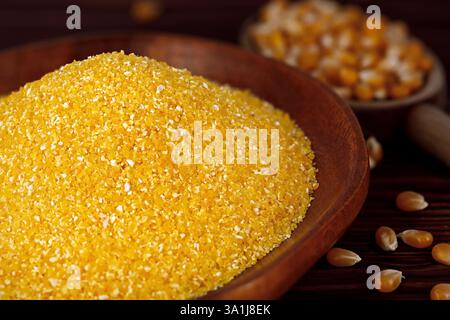 Grains de maïs dans un bol en bois à côté des grains de maïs secs dans une cuillère en bois sur une table rustique Banque D'Images