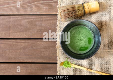 Tazza di tè matcha fresco, frusta di bambù e polvere verde su tavolo di legno bianco, vista dall'alto. Spazio per il testo Banque D'Images