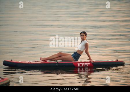 La jeune femme est sur des planches de sup dans le lac. Banque D'Images