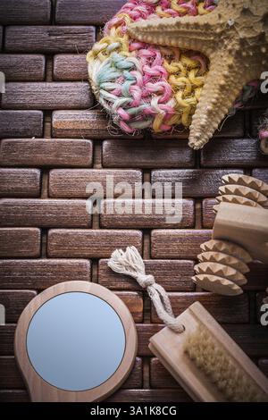 Brosse de pelage masseur Handglass et éponge de bain colorée sur tapis de table en bois texturé concept sauna Banque D'Images