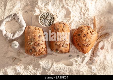 Rouleaux de citrouille dorés et moelleux reposant sur un lit de farine à la boulangerie. Une délicieuse création de boulangerie. Banque D'Images