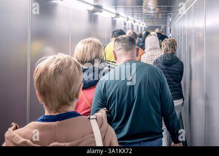 Une grande foule de voyageurs impatients attendant patiemment de monter à bord de leur prochain vol dans un tunnel d'aéroport moderne animé gens, passagers dans une file d'attente, w Banque D'Images