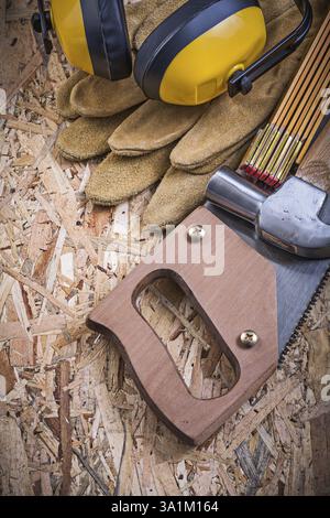 Gants de protection en bois mètre scie à main griffe marteau protecteurs d'oreilles sur OSB Banque D'Images